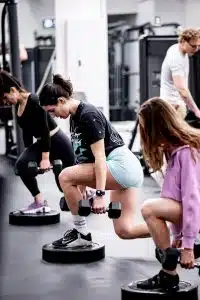 Womens small group training class performing dumbell lunges